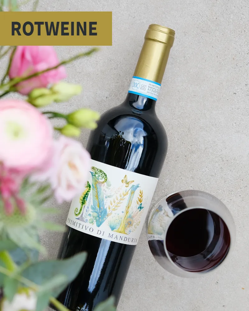 Blumen, eine Flasche Rotwein und ein Weinglas