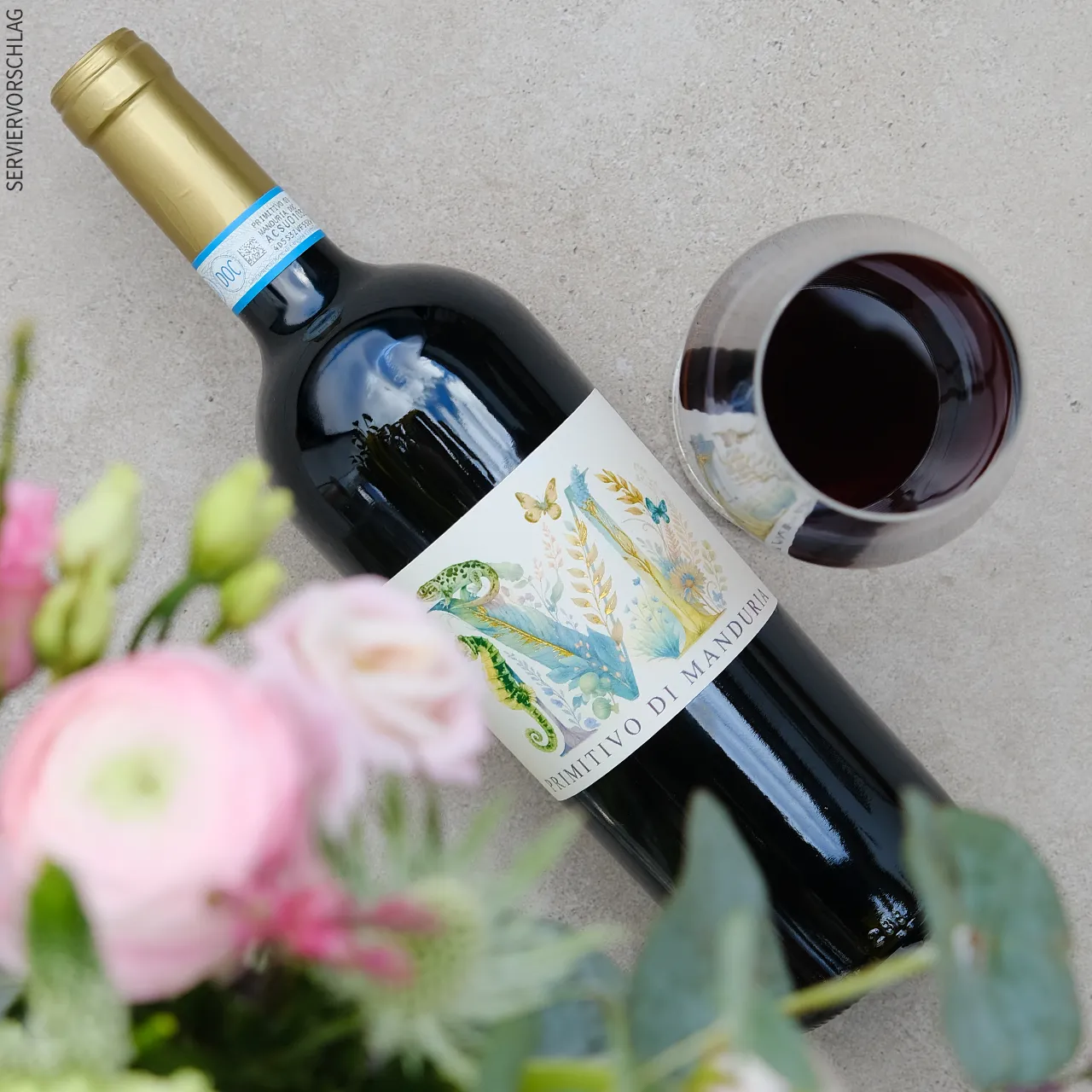 Ausdrucksstarker Rotwein mit langem, würzig-fruchtigem Nachhall Blumen, eine Flasche Primitivo di Manduria und ein Glas Rotwein