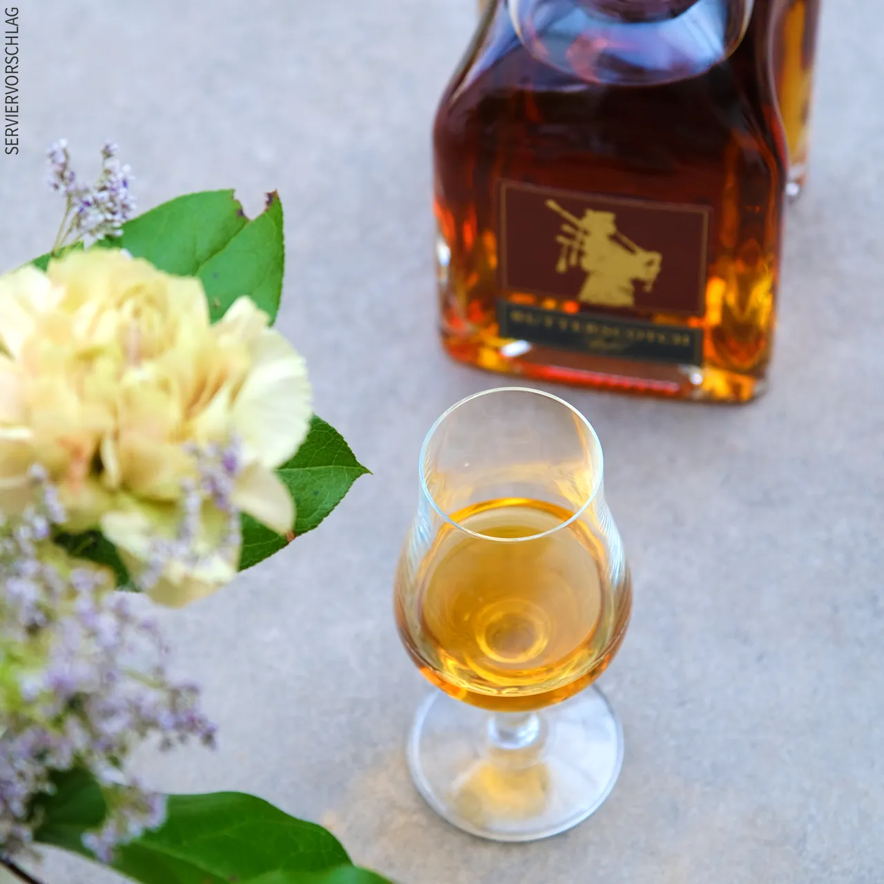 Den muss man probieren Blumen, ein Likörglas und eine Flasche Butterscotch Apfel Likör