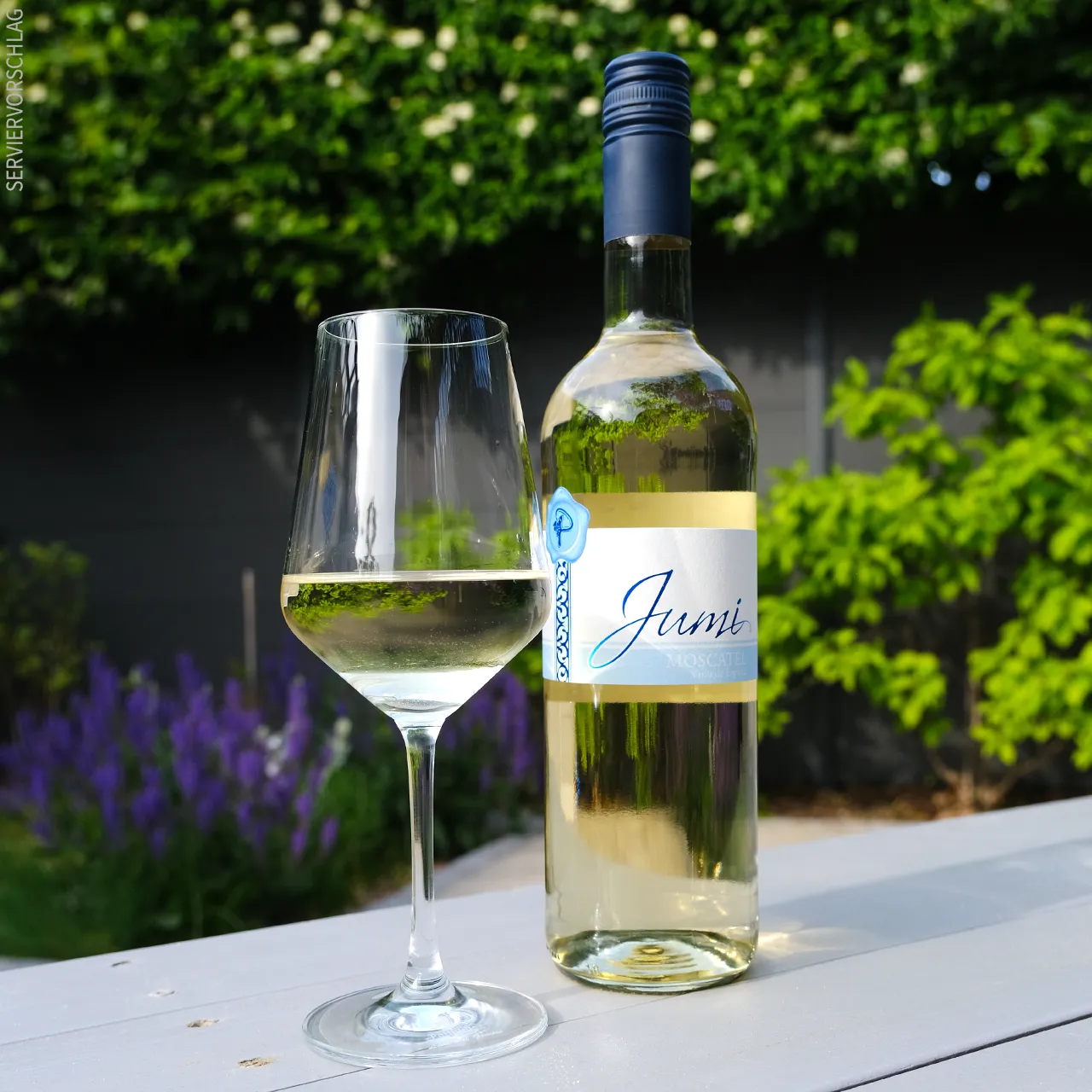 Blumen, eine Flasche Jumi Moscatel und ein Glas Weißwein