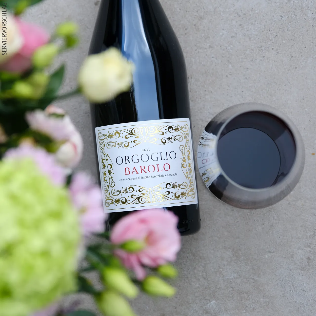 Blumen, eine Flasche barolo und ein Glas Rotwein