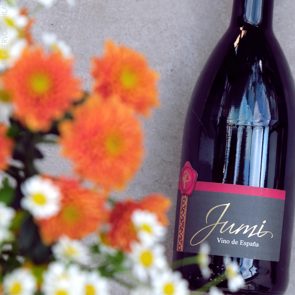 Dieser Wein leuchtet in einem kraftvollen und dunklem Kirschrot und begeistert mit feinen Purpurreflexen Ein Blumenstrauß und eine Flasche Jumi