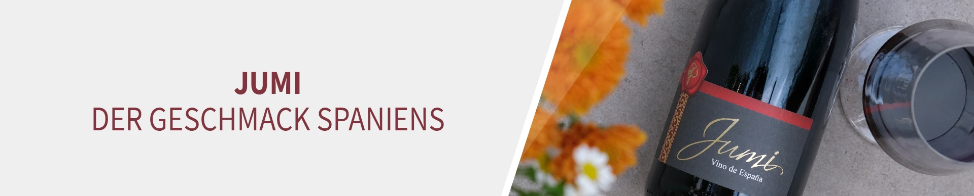 Blumen, ein Glas Rotwein und eine Flasche Jumi 