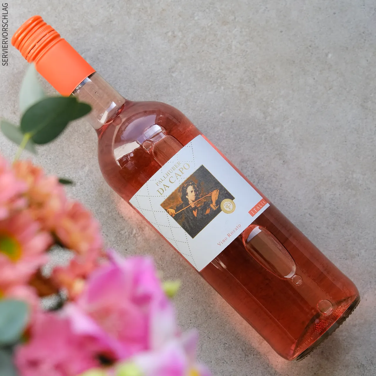 Blumen, eine Flasche Roséwein und ein Glas mit Wein